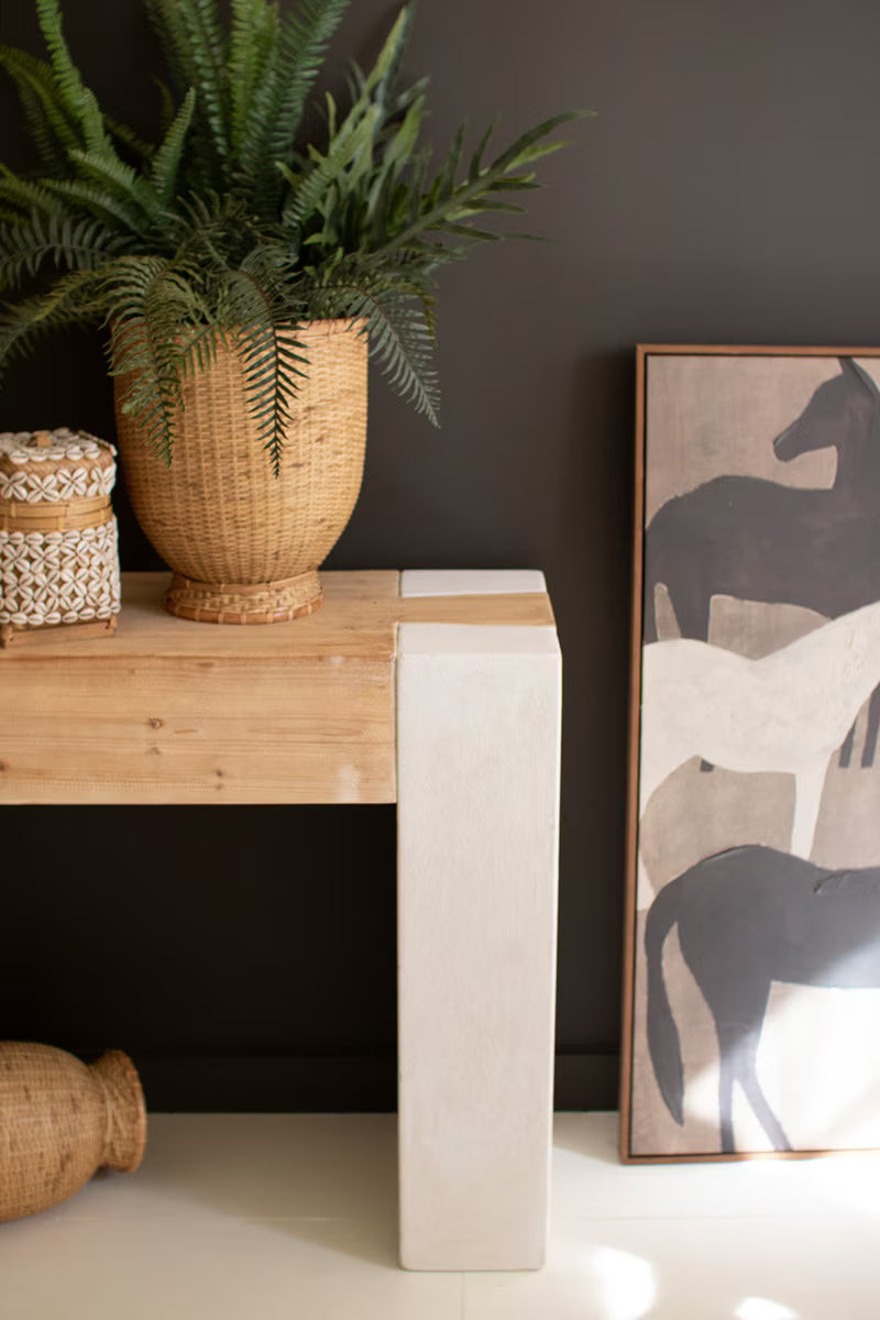 Decorative setting with a wooden console table, potted plant and framed artwork of horses