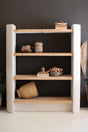 Wooden bookshelf with decorative items against a dark wall