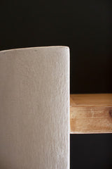 Close-up of a textured white surface next to a wooden surface on a dark background