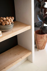 Wooden shelves with decorative items in a minimalistic setting - close-up view of right corner of shelf
