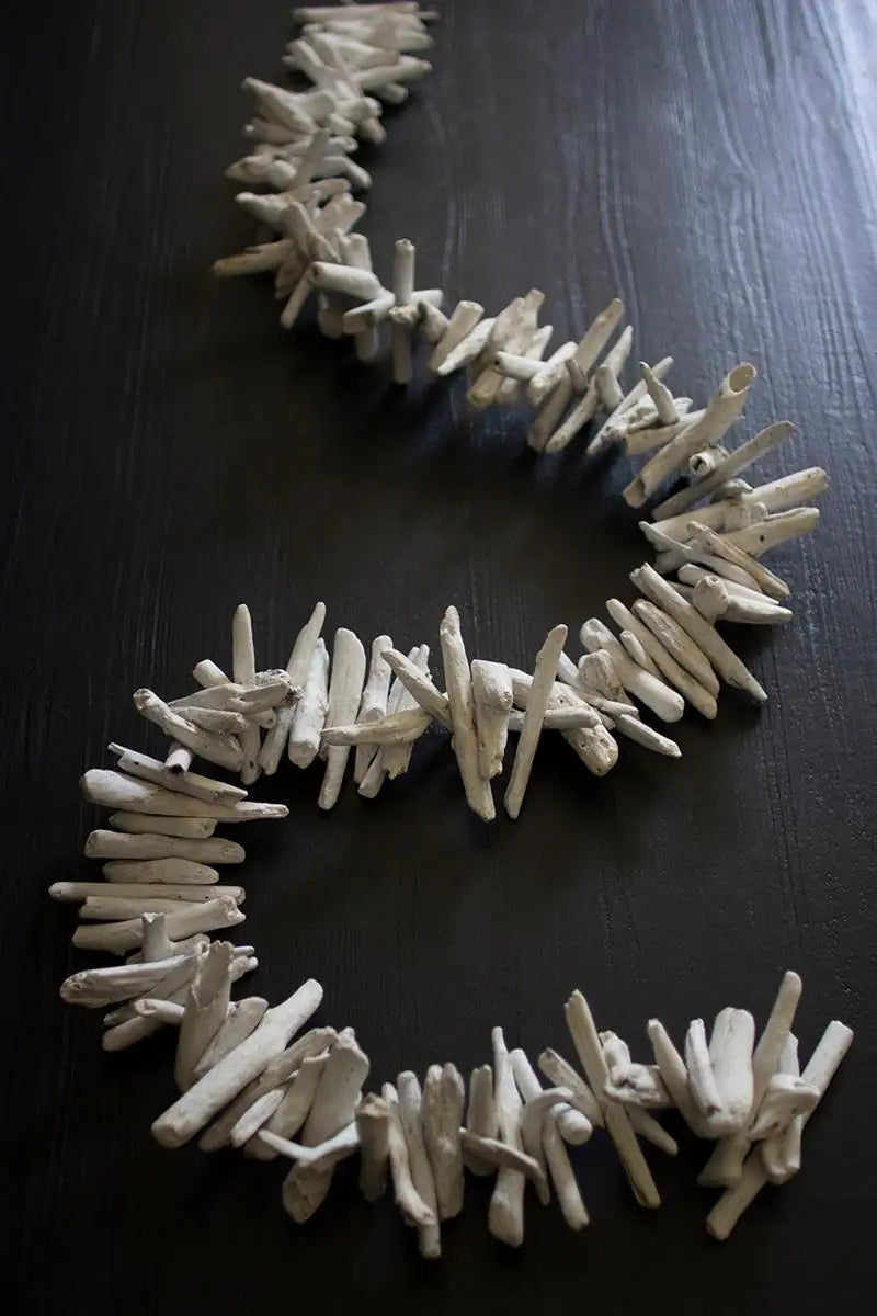 off white driftwood garland laying on dark brown table