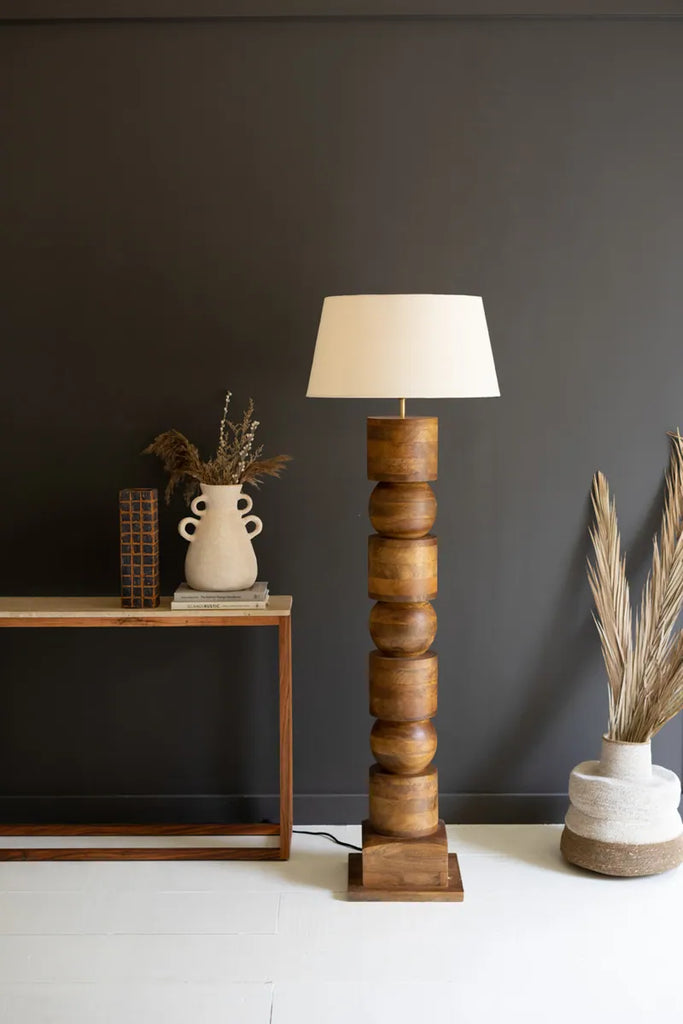 wood column floor lamp with alternating orb cylinder shapes and off white lamp shade