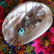 long necklace photographed on top of mother-of-pearl shell