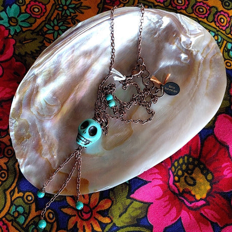 long necklace photographed on top of mother-of-pearl shell