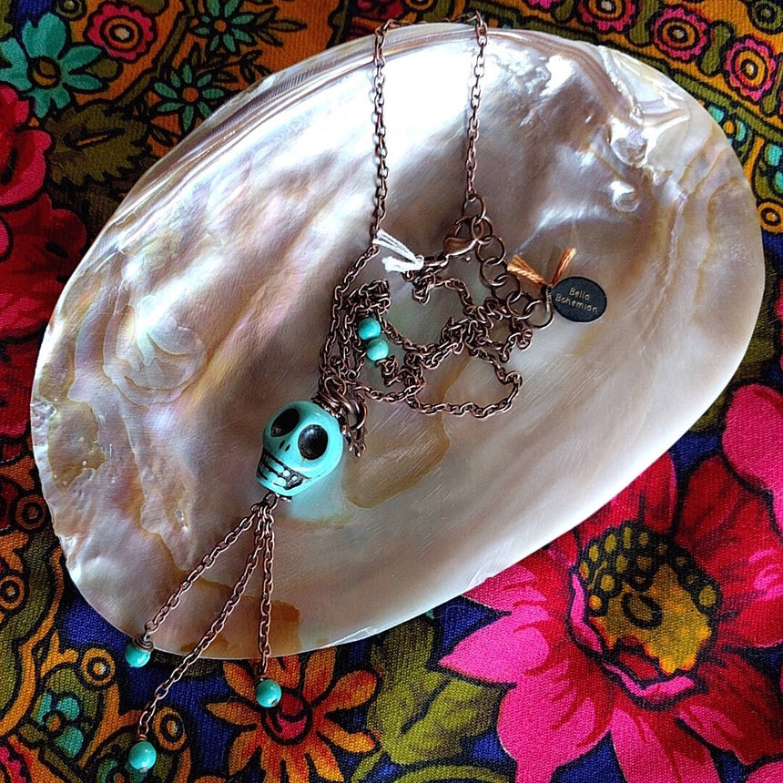 long necklace photographed on top of mother-of-pearl shell