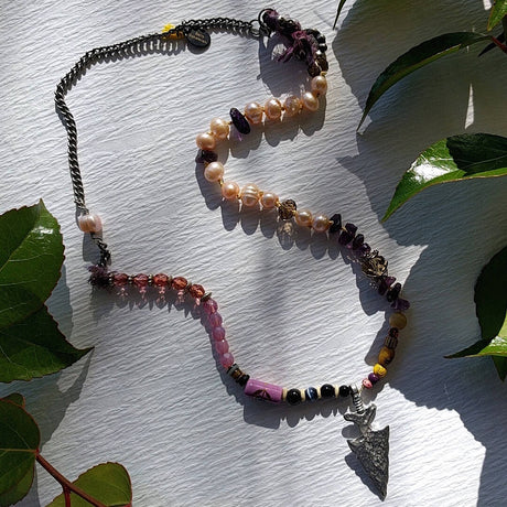 asymmetrical mixed media necklace photographed against plain background
