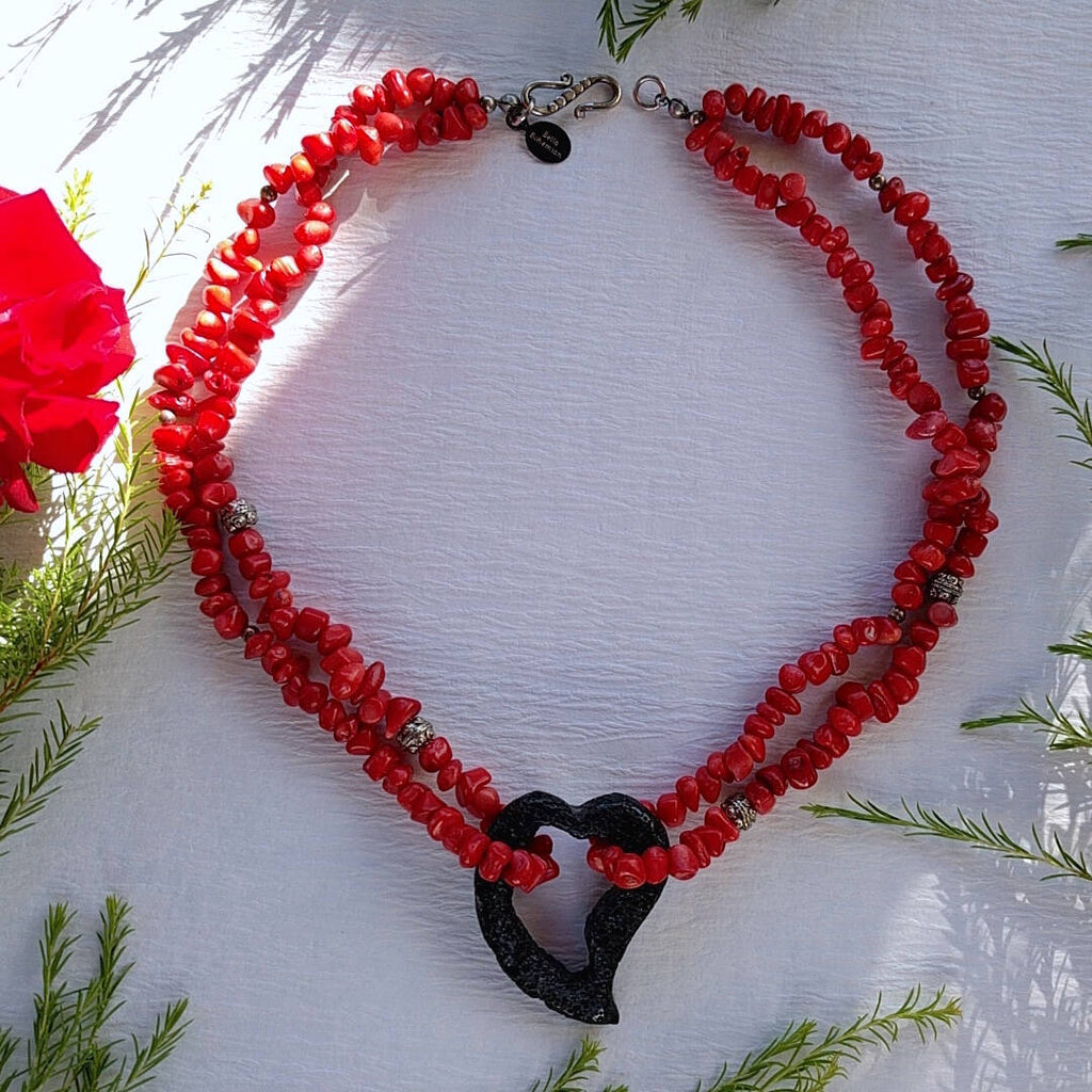 double strand coral necklace with lava heart photographed on plain background