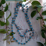 long handmade turquoise nugget necklace with Czech glass on a rustic white wood background