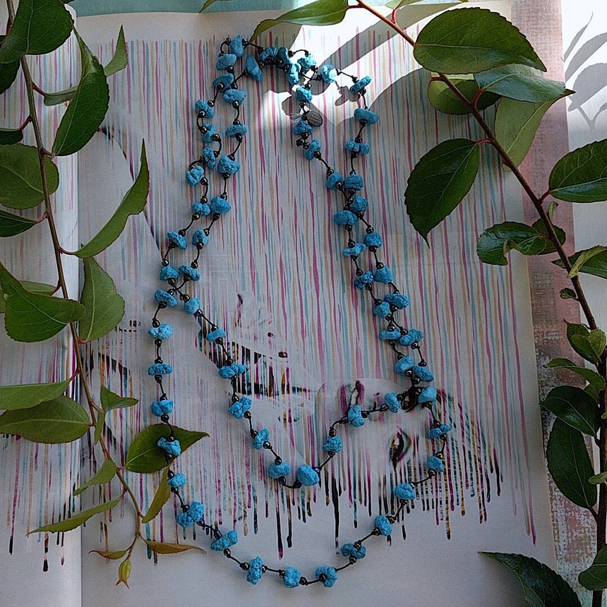 long handmade turquoise nugget necklace with Czech glass on a rustic white wood background