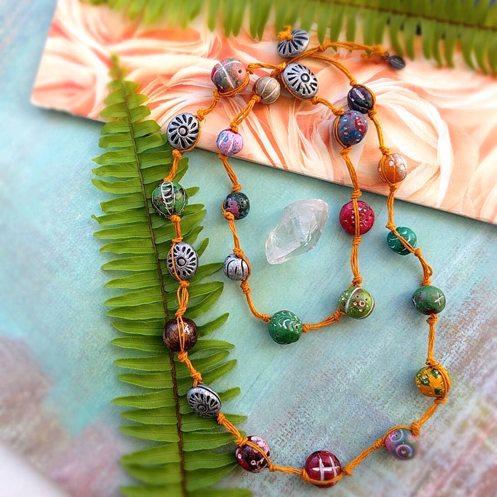 long rustic strand necklace hand-knotted with an orange hemp cord and multi-colored hand carved clay stones