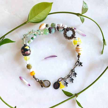 handmade bracelet with lamp work glass, white and green Czech glass beads, orange, faceted round purple and green Ghana beads, antique brass caps
