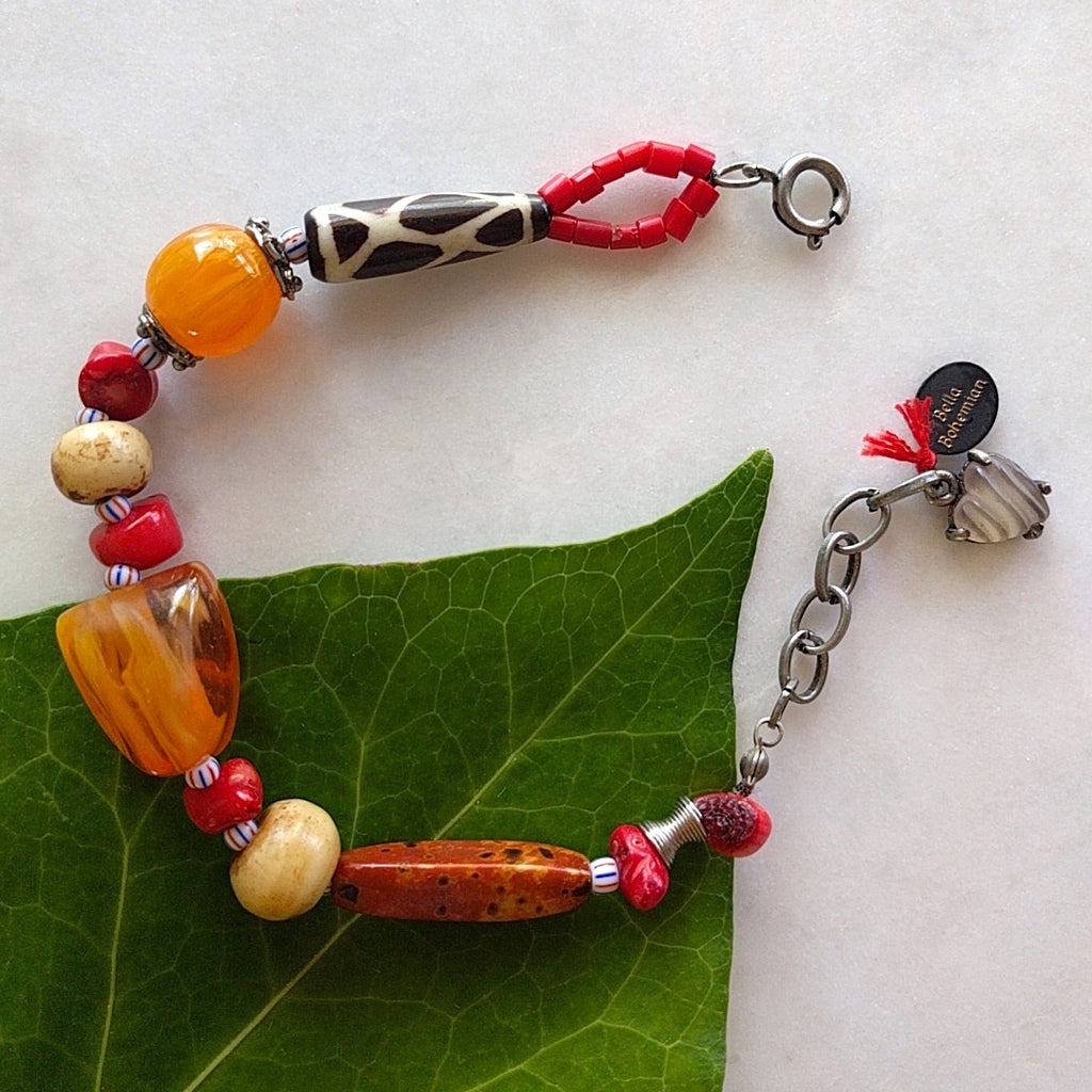 handmade bracelet on black waxed thread with African amber beads, red corals, round ivory bone beads, Ghana colored seed beads, silver-plated caps