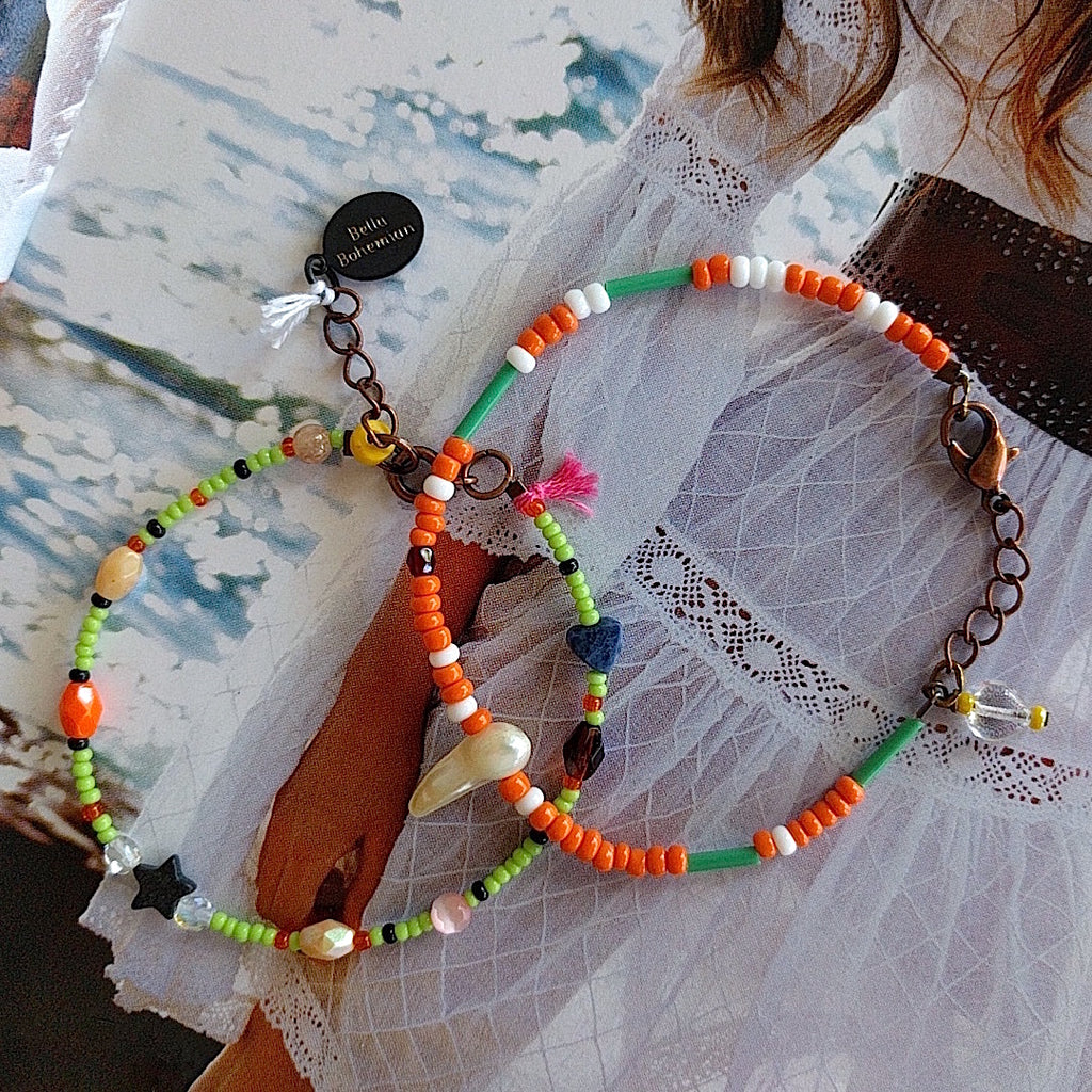 set of 2 handmade bracelets with white, creme and orange glass beads, tiny dark blue heart and tiny black star on alternate background