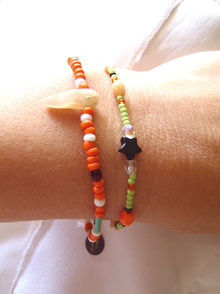 set of 2 handmade bracelets with white, creme and orange glass beads shown on a lady's wrist
