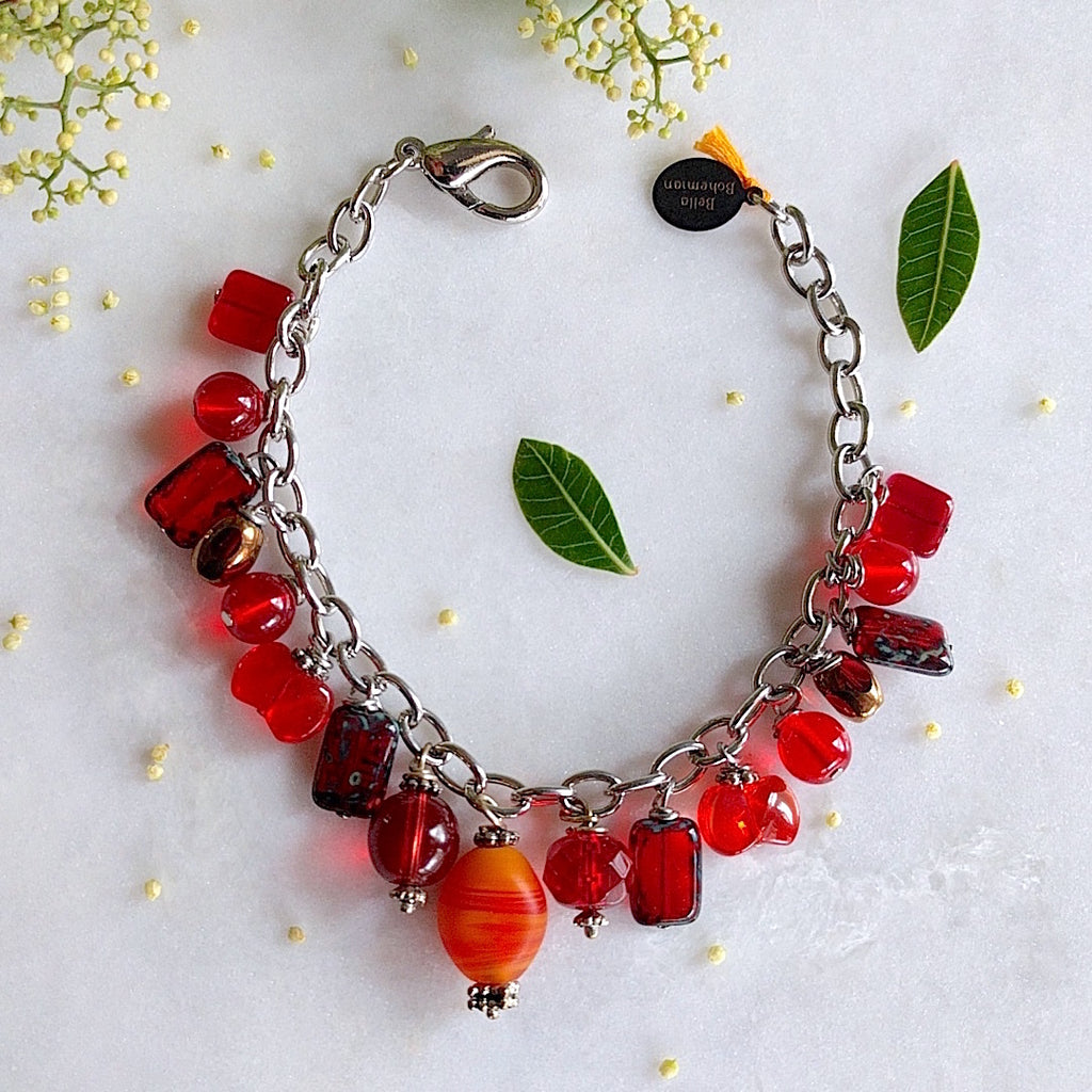 handmade silver-plated charmed bracelet with fire red polished Czech glass beads, and an oval orange matte abstract glass bead center charm