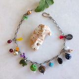 charm bracelet with peacock, burgundy fresh water pearls, silver-plated bell, jade bear, green skull, abstract colored heart, turquoise chips