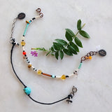 set of bracelets, one with black cotton thread, the other with multicolored seed and glass beads