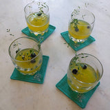 set of four teal green coasters shown with drinks on top