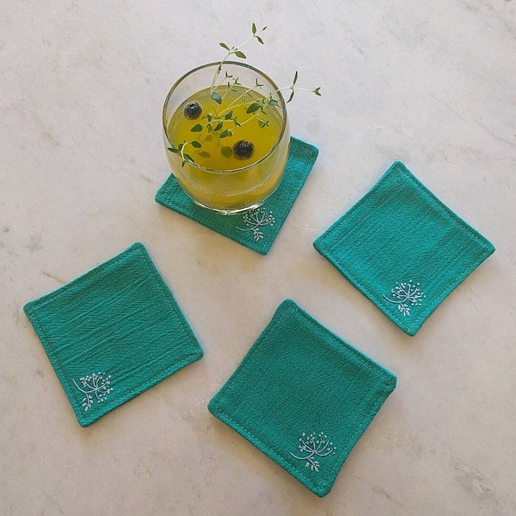 set of four teal green coasters one shown with drink on top