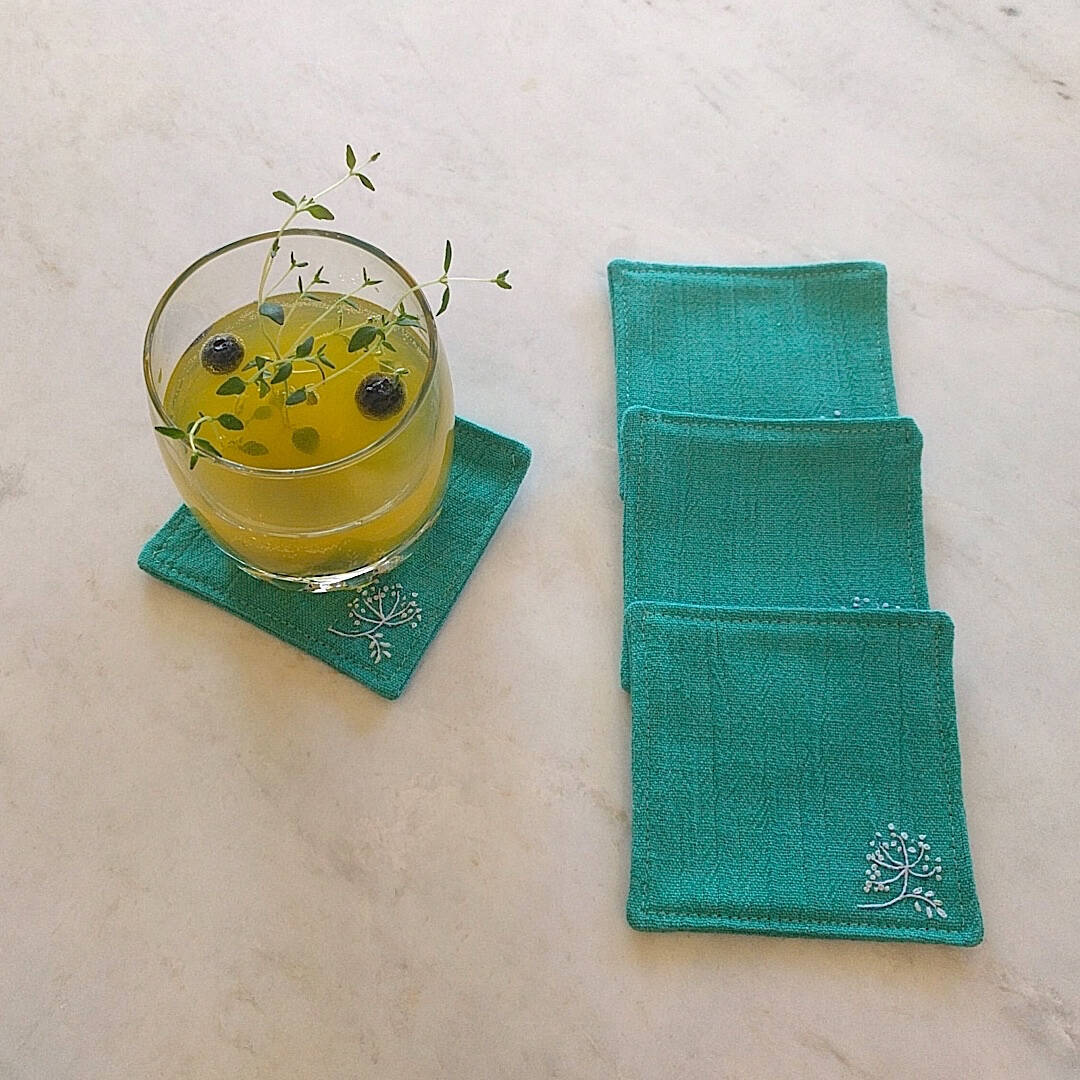 set of four teal green coasters one shown with drink on top (2)