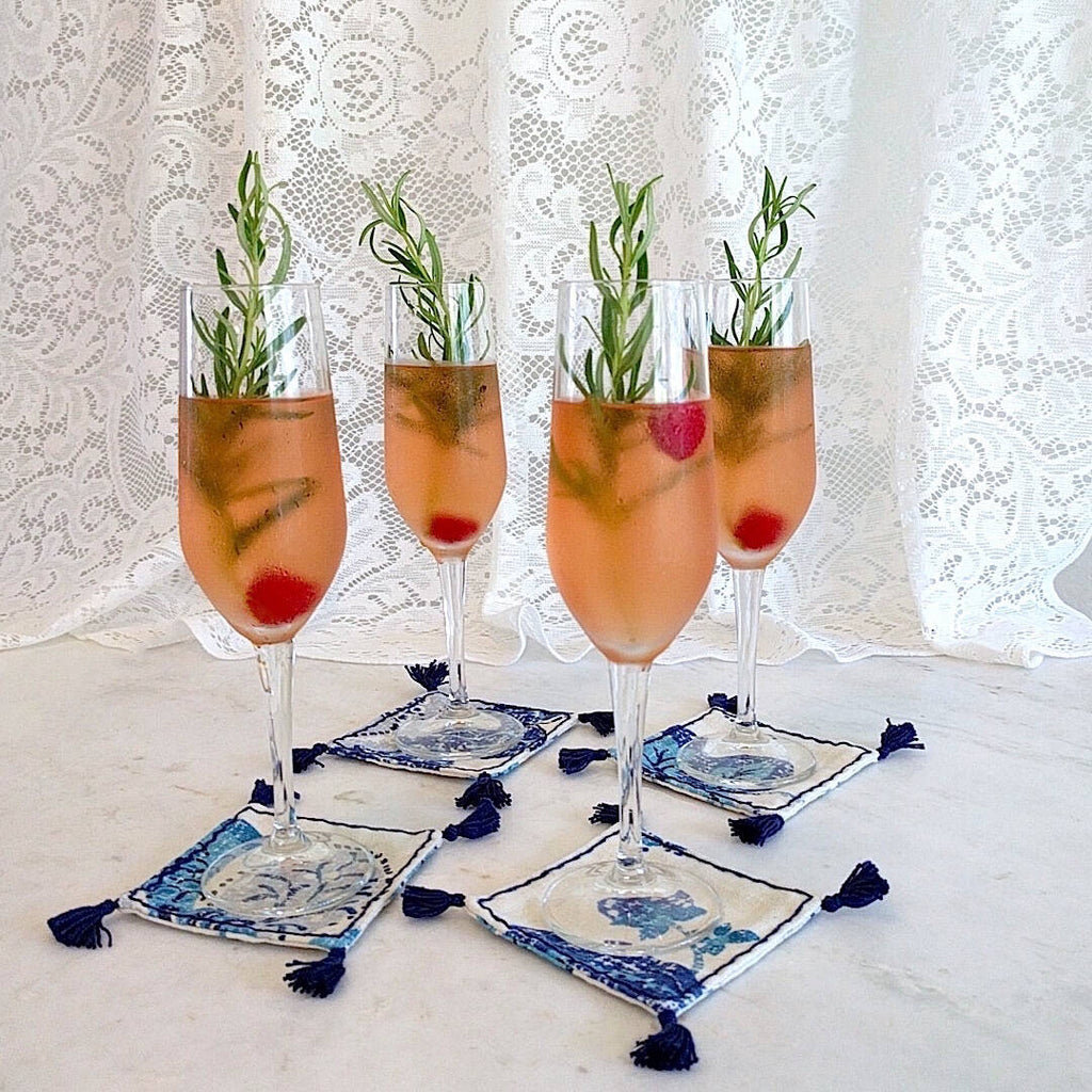 4 square boho in royal blue and ivory heavy linen colored coasters shown under champagne flute drinks