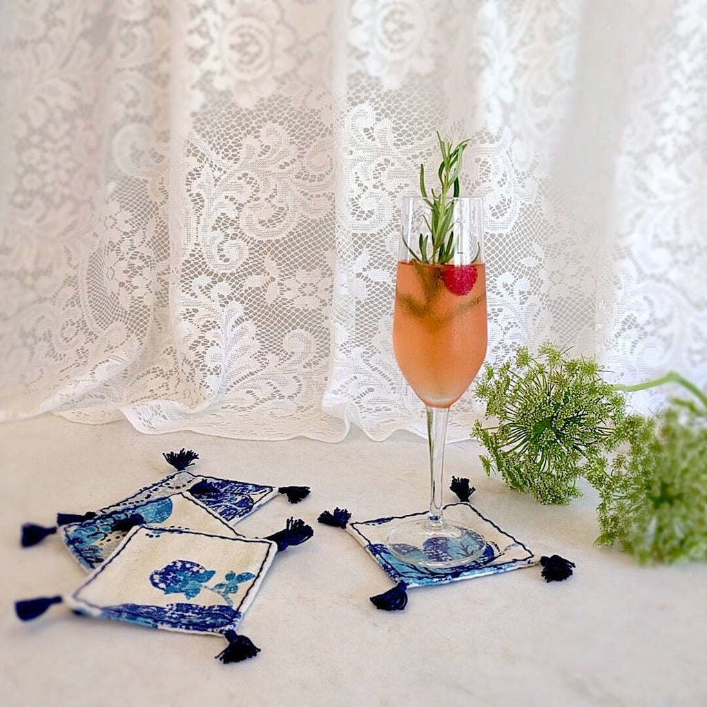 4 square boho in royal blue and ivory heavy linen colored coasters, one shown with champagne flute drink on top