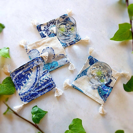 4 square boho royal blue and ivory colored heavy linen coasters 2 shown under a filled drinks (2)