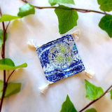 single square boho royal blue and ivory colored heavy linen coaster with filled drink - top down view