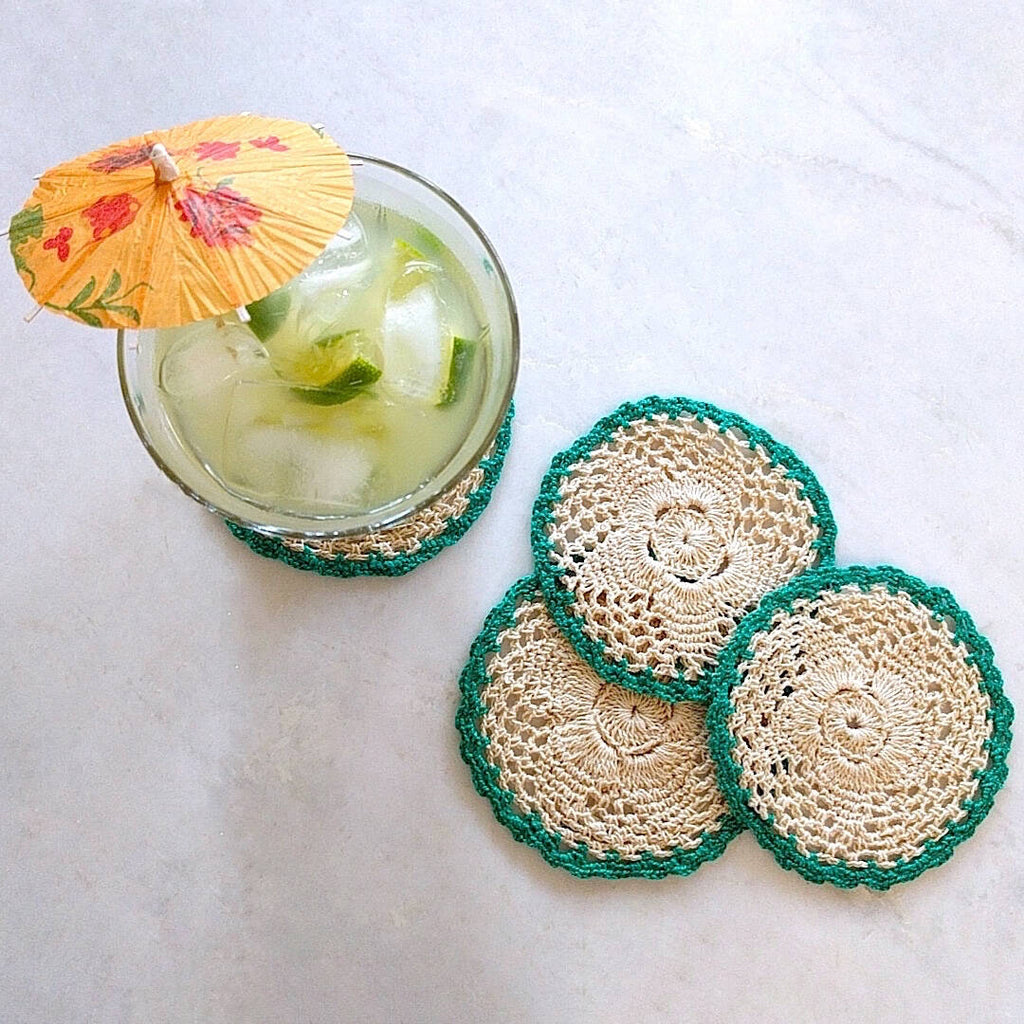 set of four round crochet cotton yarn coasters in natural tan color with teal border - top down view