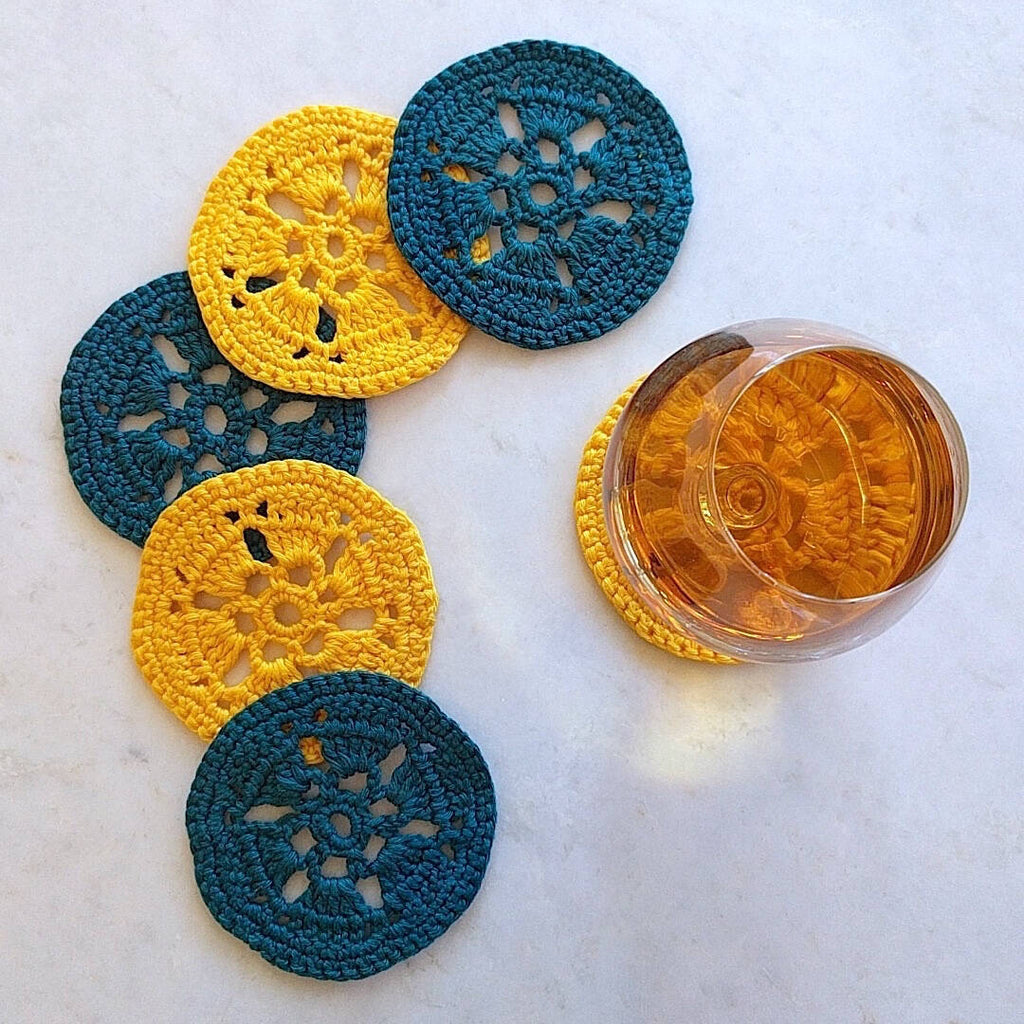 two bright yellow and two earth dark green crocheted coasters - top down view