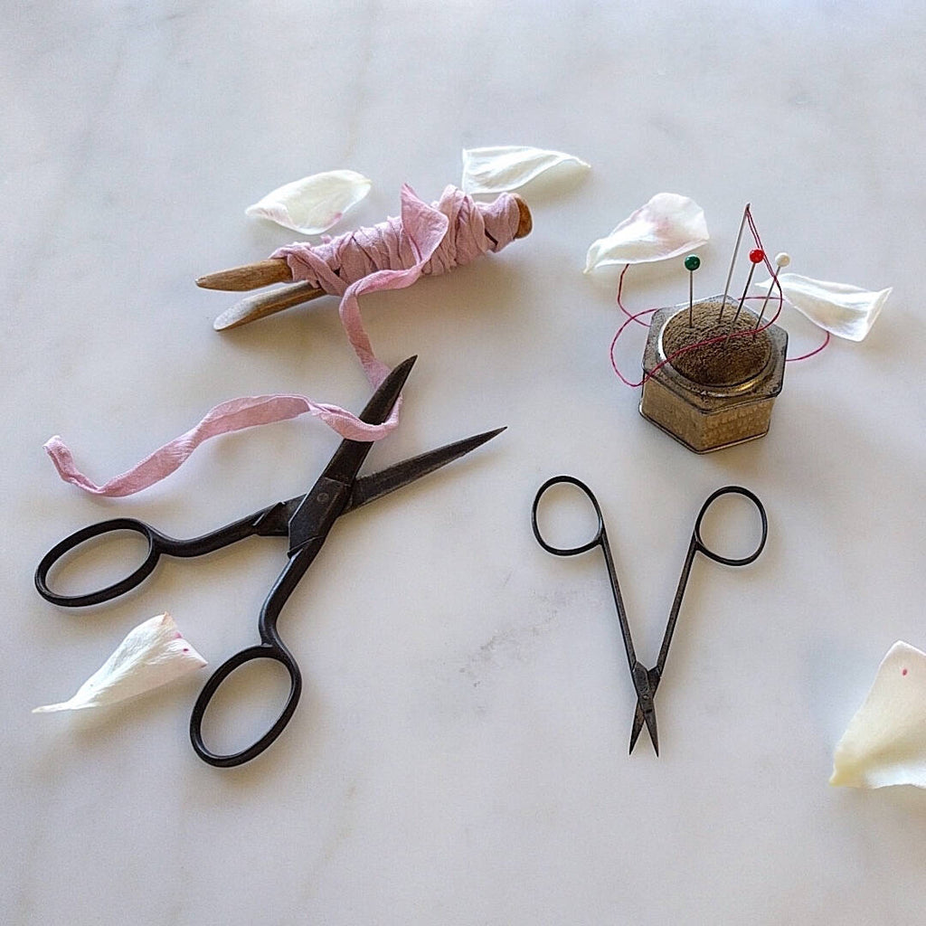 antique German sewing kit with two scissors a pin cushion and pink ribbon