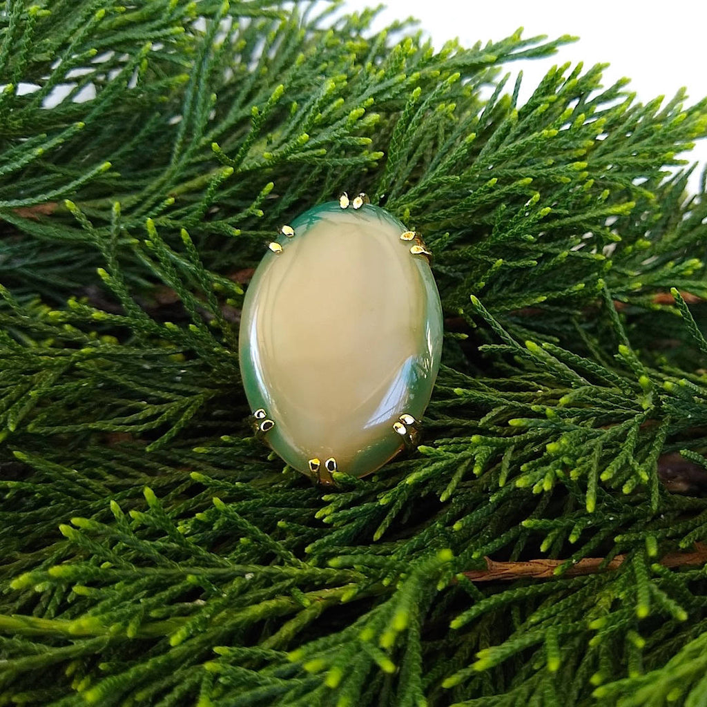 top down view of oval shaped dark green border with milk colored middle agate adjustable cocktail ring