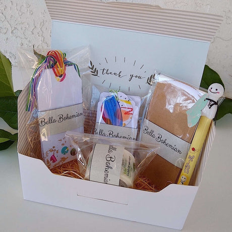 confetti and gold foil gift cards, white gift tags, mini envelopes, Japanese washi tape, Japanese sunny doll black pen all plastic wrapped, standing in a gift box