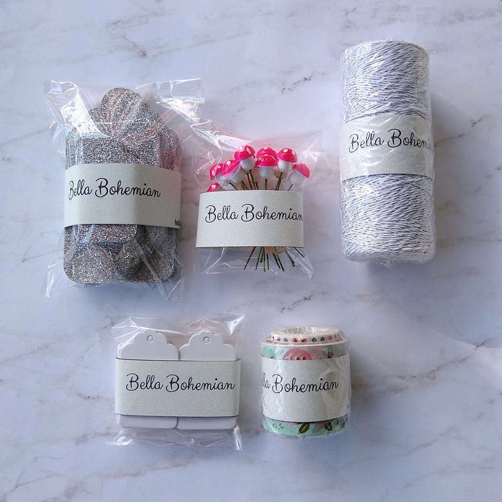 silver luxe glitter gift cards, white hang tags, German cotton spun mushrooms, metallic glitter bakers twine plastic wrapped laid out flat