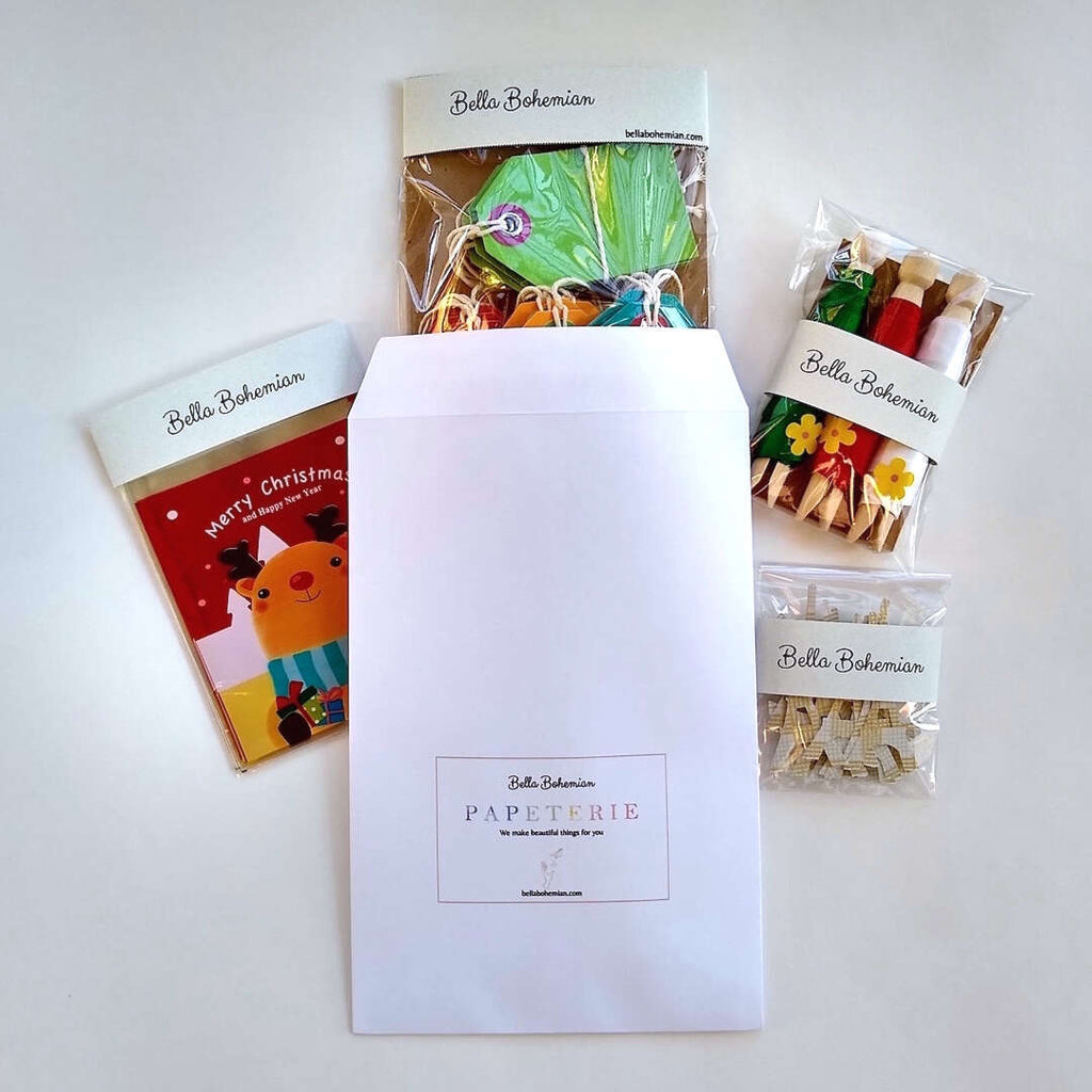 Bella Bohemian envelope with wrapped packages of Christmas favor bags, gift ribbons, gift tags and eiffel tower confetti
