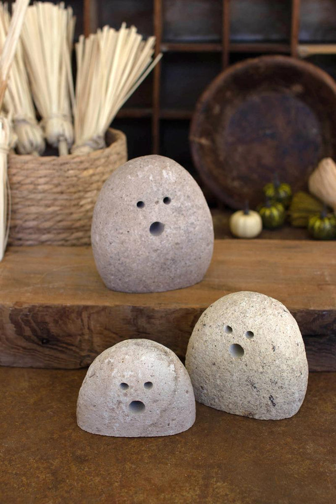 set of 3 river rock ghosts - one sitting elevated on a slab of wood
