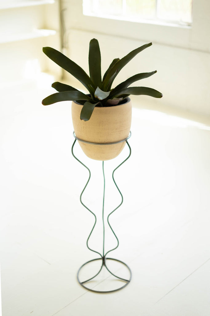 tall ivory and black clay pot on squiggly 3 legged stand
