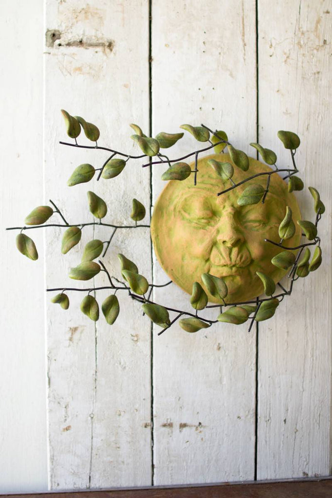 clay sun face with leaves blowing in the wind
