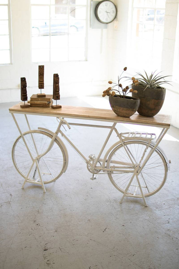 wood shelf supported by white repurposed bicycle frame